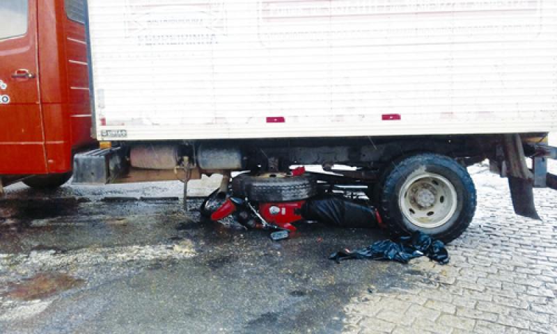 Motoqueiro para embaixo de caminhão em acidente